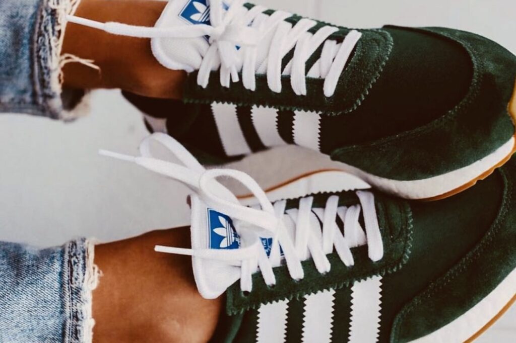 Two feet in black and white sneakers with their toes overlapping